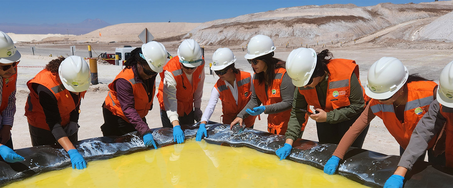 students on work site with gloved hands in yellow liquid